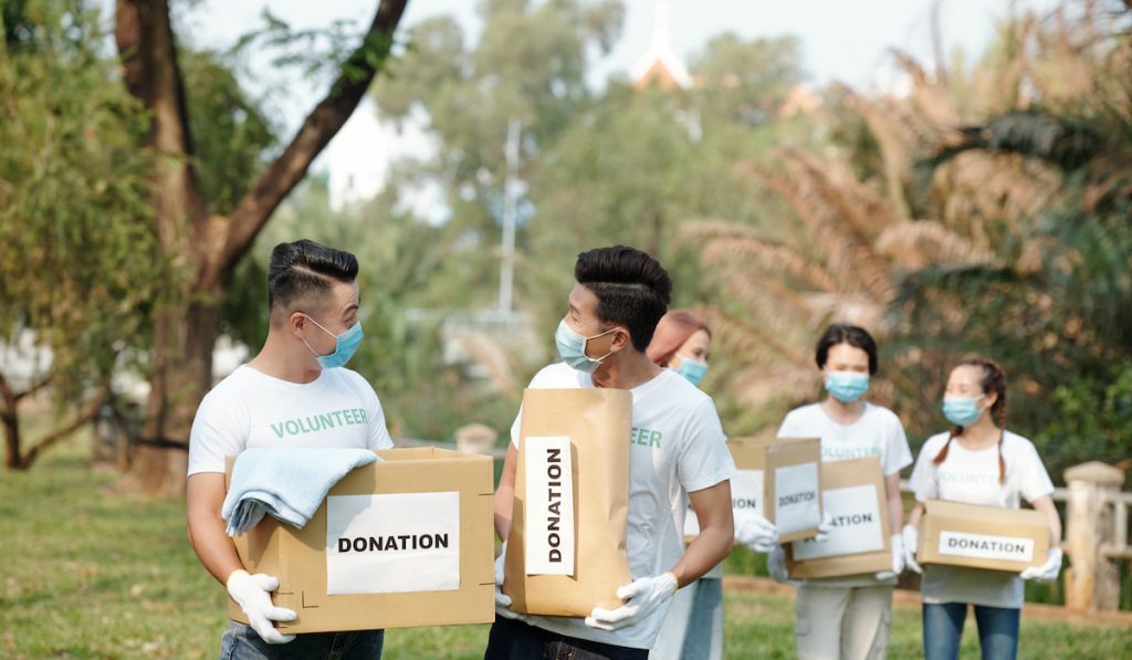 Teenager Volunteers carrying boxes with clothes donated by people 