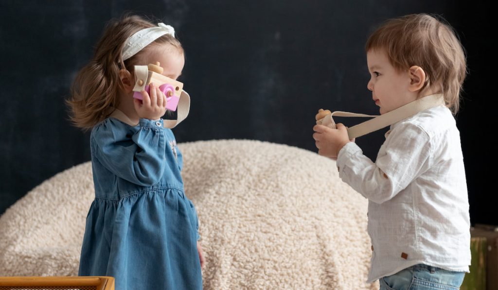 Toddler kids playing with toy cameras on a black background
