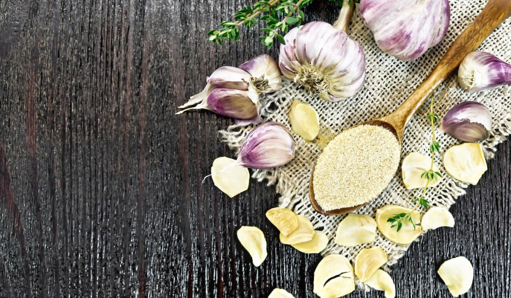 Top view of Garlic cloves and Garlic ground in spoon on black board