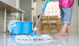 Young woman cleaning floor with mop and bucket