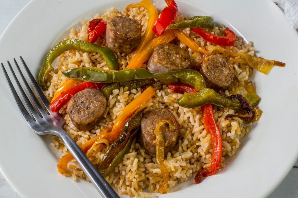 brown rice with sautéed onions and peppers top with sausages - 