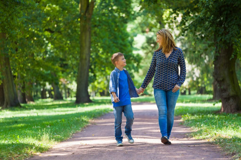 single mom with son walking in the park holding hands