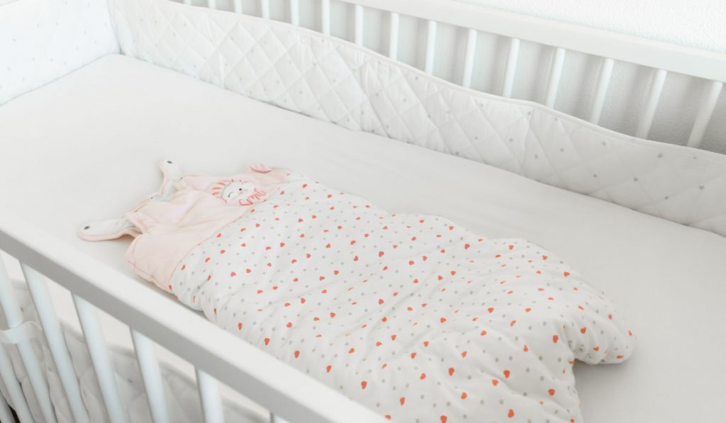 white baby bed with sleeping bag setup